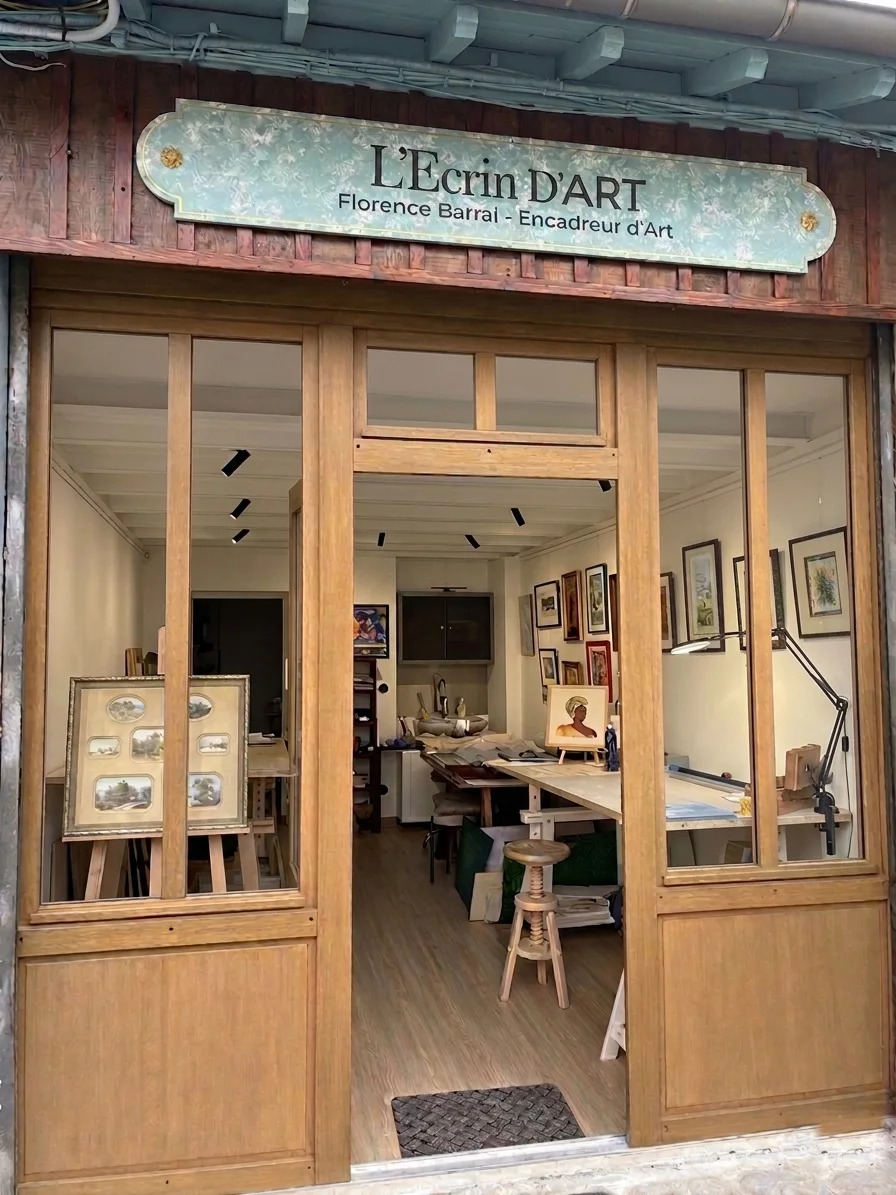 La vitrine de L'Écrin d'Art : enseigne fleurie, façade en bois, atelier ouvert sur la rue