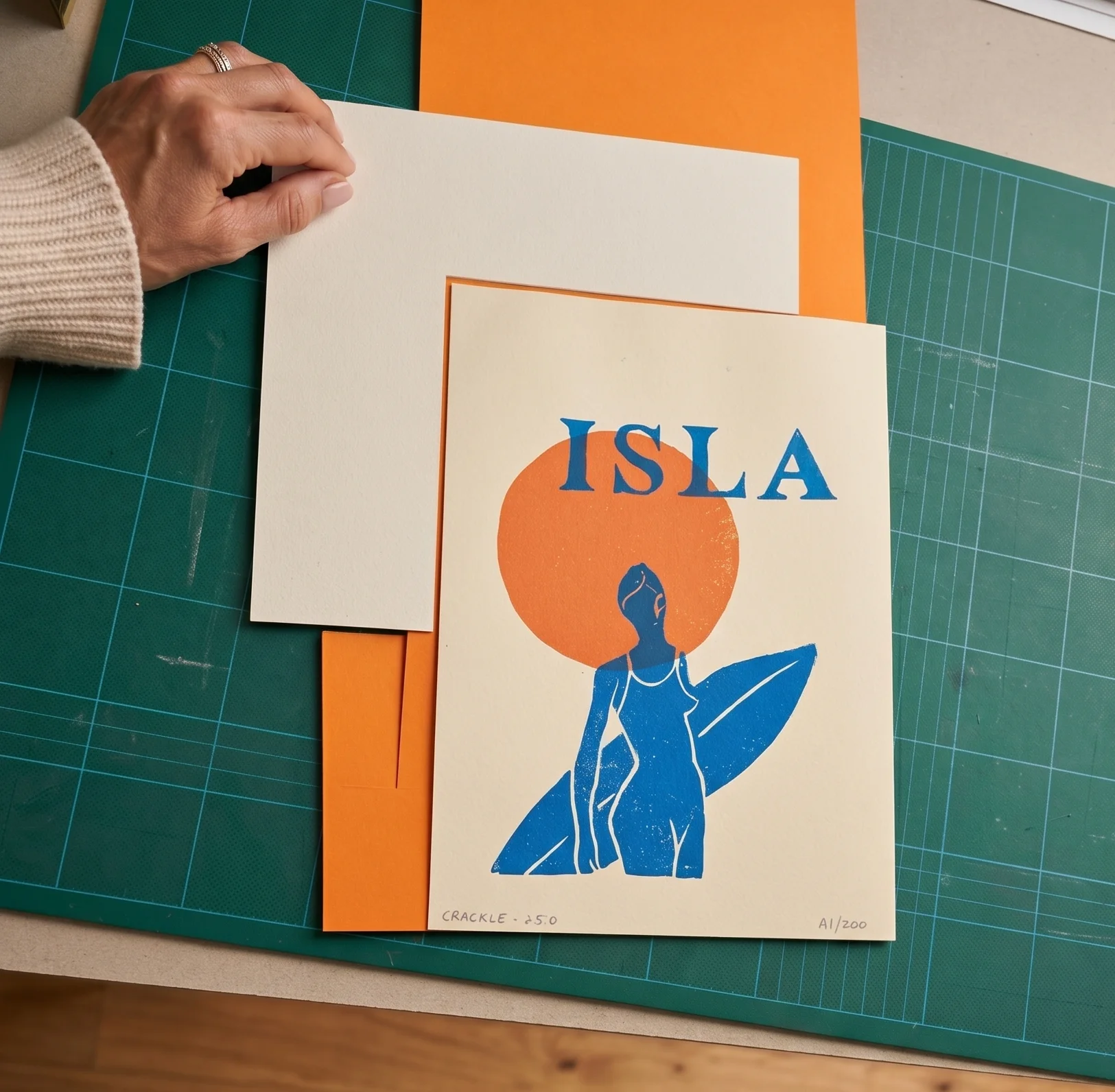 Vue de dessus de l'atelier : la sérigraphie Isla en cours d'encadrement sur un tapis de découpe