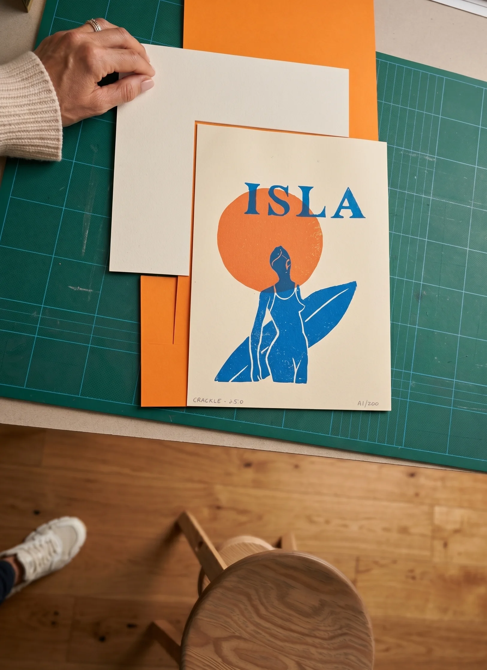Vue de dessus de l'atelier : la sérigraphie Isla en cours d'encadrement sur un tapis de découpe