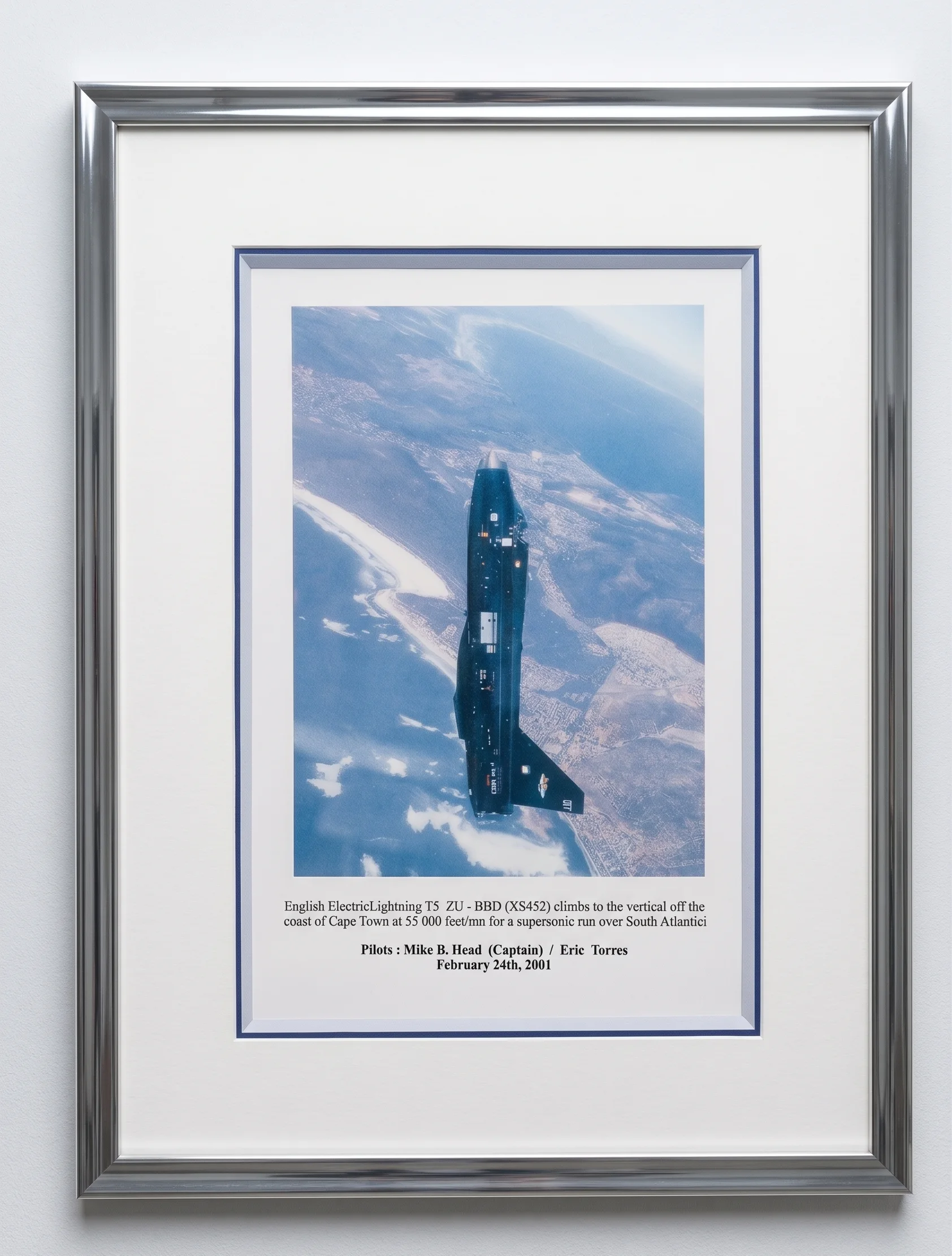 Photographie d'un avion English Electric Lightning en vol vertical au-dessus du Cap, encadré dans un cadre argenté avec double passe-partout